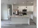 This bright kitchen features white cabinets, a stainless steel refrigerator, pendant lighting, and a breakfast bar at 13566 Sw 43Rd Cir, Ocala, FL 34473