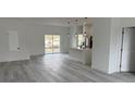An open-concept living room with light gray flooring, white walls, and a view of the kitchen at 13566 Sw 43Rd Cir, Ocala, FL 34473