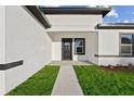 A close-up of a home's front entrance, showing a well-maintained lawn and clean, simple black and white design at 13592 Sw 43Rd Cir, Ocala, FL 34473