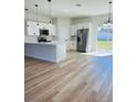 Open-concept kitchen featuring stainless steel appliances, white cabinets, quartz countertops, and wood-look flooring at 13592 Sw 43Rd Cir, Ocala, FL 34473