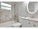 Bathroom with tiled shower and tub, white vanity, and oval mirror providing a clean aesthetic at 1797 31St Nw St, Winter Haven, FL 33881
