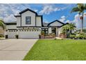 Charming home with a three-car garage, striking black and white accents, and beautiful front yard landscaping at 3180 Pawleys N Loop, St Cloud, FL 34769