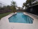 Relaxing in-ground pool with light blue water and a stone border with lush grass and wooden fence at 110 Kasey Dr, Orlando, FL 32807