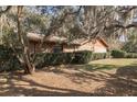 Landscaped yard featuring mature trees and bushes surrounds this single story brick home at 1101 N Valencia Ave, Howey In The Hills, FL 34737