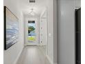 Bright hallway featuring light wood floors, modern lighting, and a front door view at 1811 Simonton Ave, Orlando, FL 32806