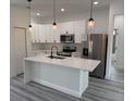 Well-lit kitchen featuring stainless steel appliances, white cabinets and island with quartz countertops and pendant lights at 2293 Sw 178Th Lane Rd, Ocala, FL 34473