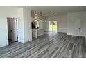 Bright living area with modern gray-tone wood floors that lead to the kitchen and sliding glass doors to the back at 2293 Sw 178Th Lane Rd, Ocala, FL 34473