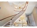 Elegant curved staircase features a grand chandelier, adding a touch of sophistication to the home's entry at 2525 Cr 543, Sumterville, FL 33585