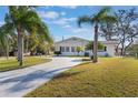 Single-story home with a long driveway, mature palm trees, and a well-manicured lawn at 29 Jasmine Dr, Debary, FL 32713