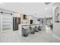 Modern, open kitchen featuring white cabinets, a marble waterfall island with seating, and stainless steel appliances at 3223 Queen Alexandria Dr, Kissimmee, FL 34744