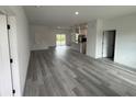 Open-concept living space featuring gray wood floors and seamless transition to kitchen and outdoor access at 4875 Sw 159Th Lane Rd, Ocala, FL 34473