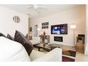 Inviting living room showcasing tile flooring, comfortable seating, a ceiling fan, and a large TV at 5384 Oakbourne Ave, Davenport, FL 33837