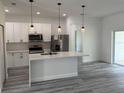 Modern kitchen features stainless steel appliances, quartz countertops, and a center island with pendant lighting at 616 Marion Oaks Ln, Ocala, FL 34473