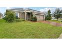 Well-manicured front yard featuring lush green grass with a brick driveway leading up to a single-story home at 841 Benjamin Trl, Davenport, FL 33837