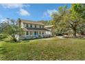 Charming two-story home featuring a full-length front porch, blue front door, and mature trees at 9332 Windy Ridge Rd, Windermere, FL 34786