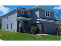 Two-story home showcasing manicured lawn, stone veneer accents, and light-gray siding at 1355 Berry Ln, Davenport, FL 33837