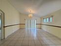 Bright living room with neutral walls, tile flooring, and a decorative chandelier at 235 Tuscany Pointe Ave, Orlando, FL 32807