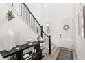 Bright foyer with staircase featuring a black iron railing and modern decor with a view to the front door at 1073 Sadler Oaks Way, Winter Garden, FL 34787