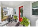 Inviting front porch with rocking chairs, potted plants, and a bright red door with decorative wreath and sidelight window at 1073 Sadler Oaks Way, Winter Garden, FL 34787