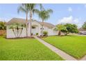 Charming one-story home with lush green lawn, palm trees, and a welcoming walkway to the entrance at 1145 Lake Rogers Cir, Oviedo, FL 32765