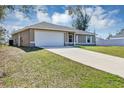 Side view of a single-story home with an attached two-car garage and driveway at 16121 Sw 24Th Court Rd, Ocala, FL 34473