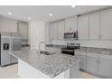 Bright open kitchen featuring stainless steel appliances, gray cabinetry, and granite counters at 3190 Viceroy Ct, Poinciana, FL 34759