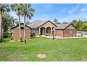 Charming single-story brick house featuring an open lawn, an American flag, and mature palm trees at 448 Warrior Trl, Deltona, FL 32725