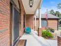 Inviting front porch with a blue chair, brick columns, and decorative planters at 448 Warrior Trl, Deltona, FL 32725