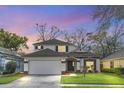 Charming two-story home with a well-manicured lawn, a two car garage, and classic architectural detailing at dusk at 5021 Sweet Leaf Ct, Altamonte Springs, FL 32714