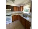 Functional kitchen with tile floor, wood cabinets, white appliances, and window for natural light at 510 Lavon Dr, Altamonte Springs, FL 32701