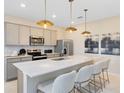 Modern kitchen featuring stainless appliances, a quartz countertop island with seating and pendant lighting at 6412 Tabebuia Pkwy, Winter Garden, FL 34787