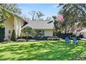 Beautifully landscaped front yard featuring a lush green lawn, mature trees, and bright blue Adirondack chairs at 1002 Versailles Ct, Maitland, FL 32751