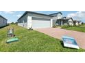 Charming home exterior with a brick driveway, lush green lawn, and a two-car garage at 2513 Merseyside Ct, Haines City, FL 33844