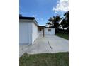 Side view of the white house with a large concrete driveway and a small garden at 2818 Geoffrey Dr, Orlando, FL 32826