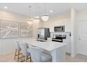 Bright kitchen with stainless steel appliances, white cabinetry, quartz countertops, and modern pendant lighting at 6424 Tabebuia Pkwy, Winter Garden, FL 34787