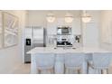 Kitchen boasts stainless appliances, white cabinetry, quartz countertops, and stylish pendant lighting at 6424 Tabebuia Pkwy, Winter Garden, FL 34787