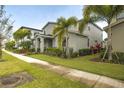 Street view of a well-maintained gray home with lush landscaping and mature palm trees at 7464 Gathering Dr, Reunion, FL 34747