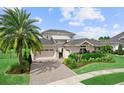 Beautiful home featuring a manicured lawn, mature palm tree, and a brick driveway leading to a spacious garage at 8614 Hata St, Orlando, FL 32827