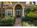 Grand entrance featuring stone columns, an arched doorway, and a decorative iron door surrounded by lush greenery at 9212 Island Lake Ct, Orlando, FL 32836