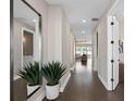 Bright hallway featuring hardwood floors, a modern mirror, potted plants, and a glimpse of the living area at 2030 Branched Oak Rd, St Cloud, FL 34771