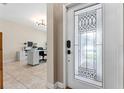 Inviting foyer with decorative glass front door, tile flooring, and view of the home office space at 4622 Fairy Tale Cir, Kissimmee, FL 34746