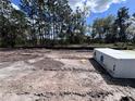 A vacant lot with tire tracks and some building materials, surrounded by tall trees under a partially cloudy sky at 5226 Prairie Preserve Run, St Cloud, FL 34772