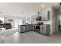 Modern kitchen with grey cabinets, stainless steel appliances, granite countertops and adjacent carpeted living space at 650 Peyton Brooke Way, Winter Haven, FL 33881