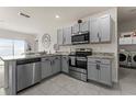 Well-lit kitchen features stainless steel appliances, grey cabinetry and a breakfast bar adjacent to laundry area at 650 Peyton Brooke Way, Winter Haven, FL 33881