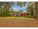 Classic brick ranch home surrounded by mature trees and a spacious front yard with seasonal leaves at 7252 June Bug Ln, Orlando, FL 32818