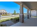 Relaxing covered front porch with brick-accented columns overlooking a well-manicured lawn and a peaceful street at 9834 Introduction Way, Orlando, FL 32832