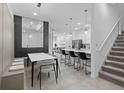 Open floor plan combines dining area with modern table set, island with bar stools, and elegant staircase at 10364 Ebb Tide Ln, Orlando, FL 32821