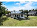 Charming home featuring a covered front porch, white siding, black window trim, and a beautifully landscaped lawn at 3512 Central Ave, Coleman, FL 33521