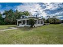 Charming home featuring a covered front porch, white siding, black window trim, and a beautifully landscaped lawn at 3512 Central Ave, Coleman, FL 33521