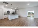 Open-concept living area with wood flooring, a kitchen view, and sliding glass doors to the yard at 411 St Johns Ln, Kissimmee, FL 34759